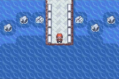 The player standing at the end of a narrow bridge surrounded by rocks in open water.